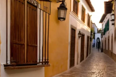 Una estrecha calle de Aracena brillaba bajo el sol crepuscular con una mezcla de luz dorada y sombras oscuras