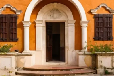 Un casco antiguo con arquitectura blanca y arcos moriscos rodeado por flores silvestres y sombreado en medio del atardecer