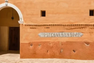 El antigo edificio de piscinas tiene una fachada desgastada con letreros y detalles corroídos por el tiempo
