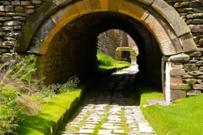 Un niño contempla la arquitectura del puente romano con detalles como piedras erosionadas y crecimientos de musgo